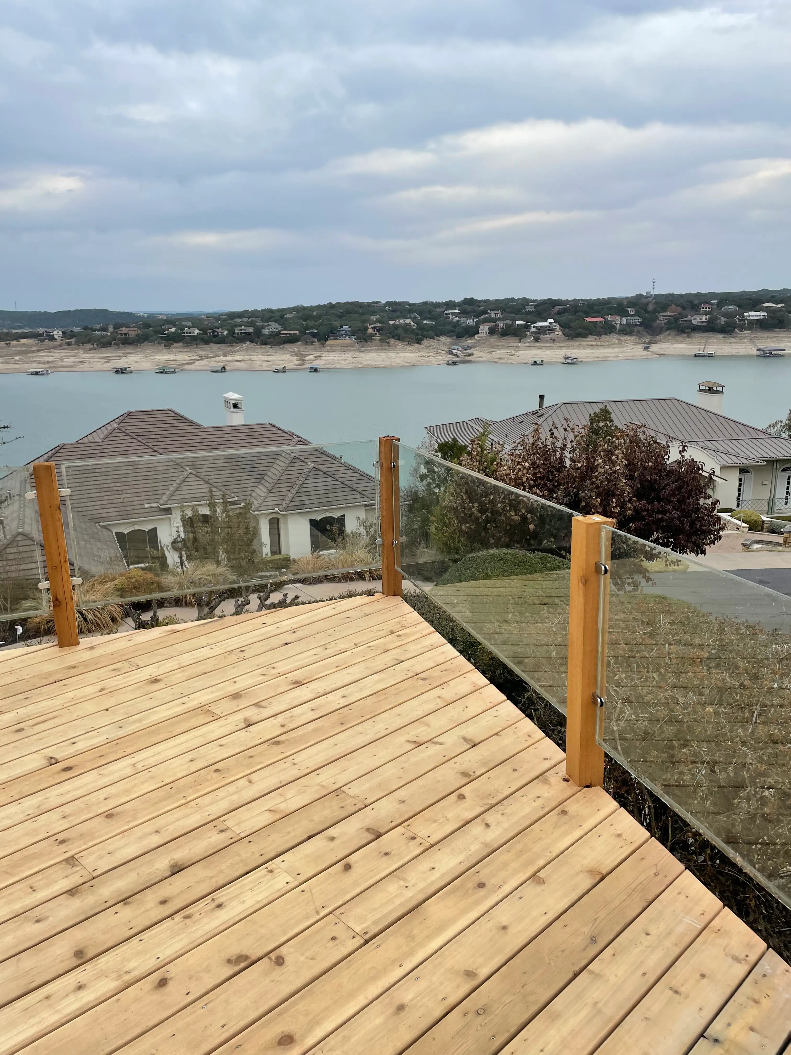 Cedar deck with glass railing looking out over rooftops to Lake Travis