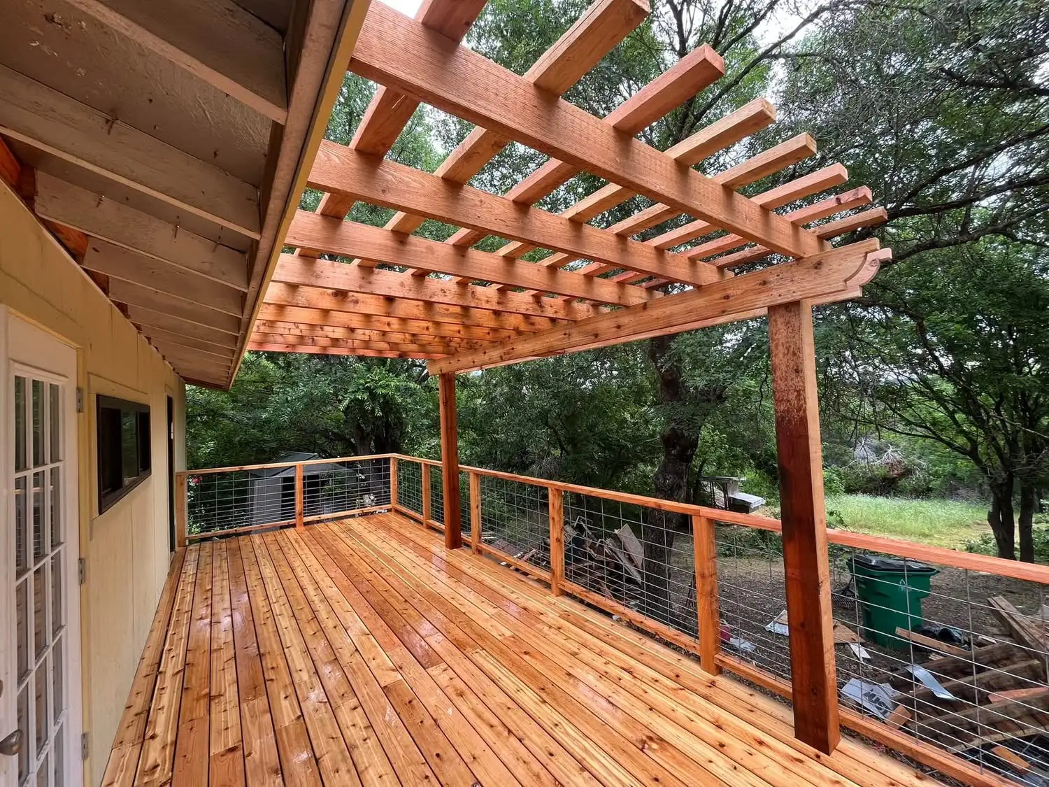 Open cedar pergola extending from a covered porch over a new cedar deck