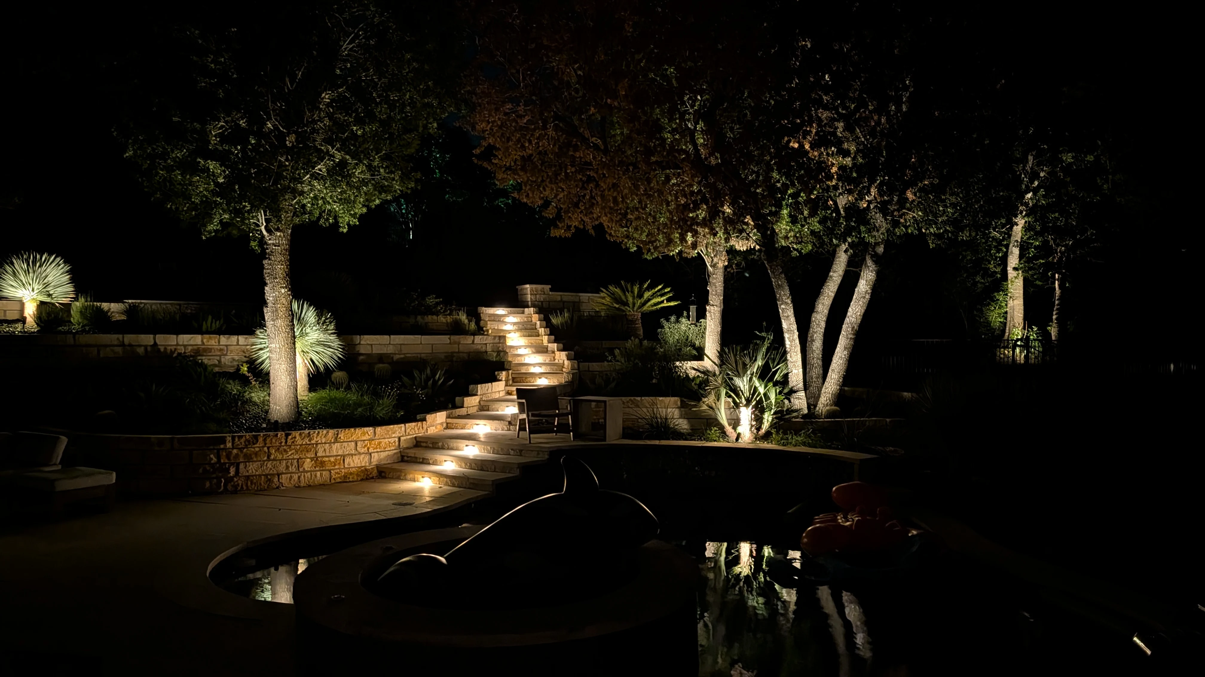 Landscape lighting showing a lit up stairway to an elevated patio.