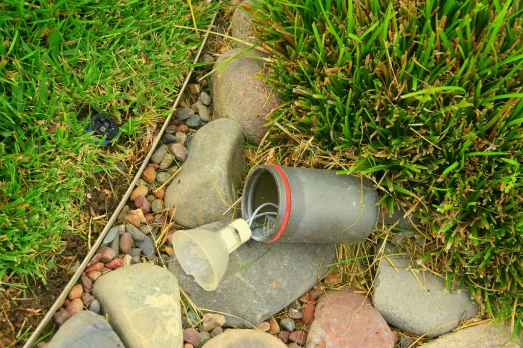 Landscape light fixture knocked loose from its stake in a bed