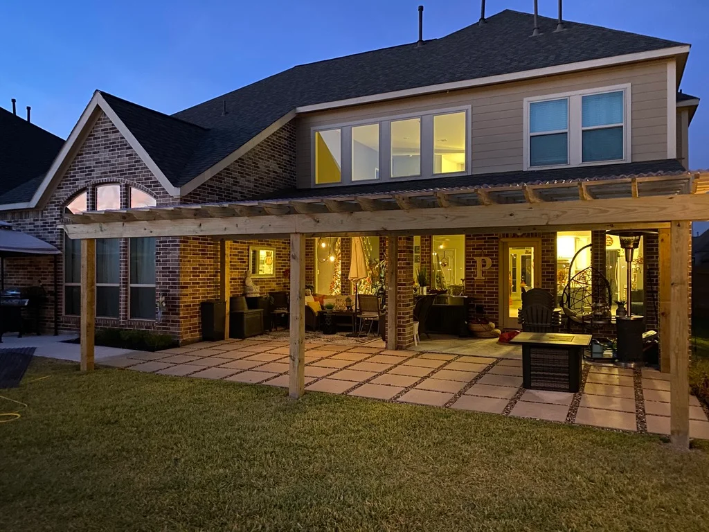 Cedar pergola over a paver patio, lit at dusk