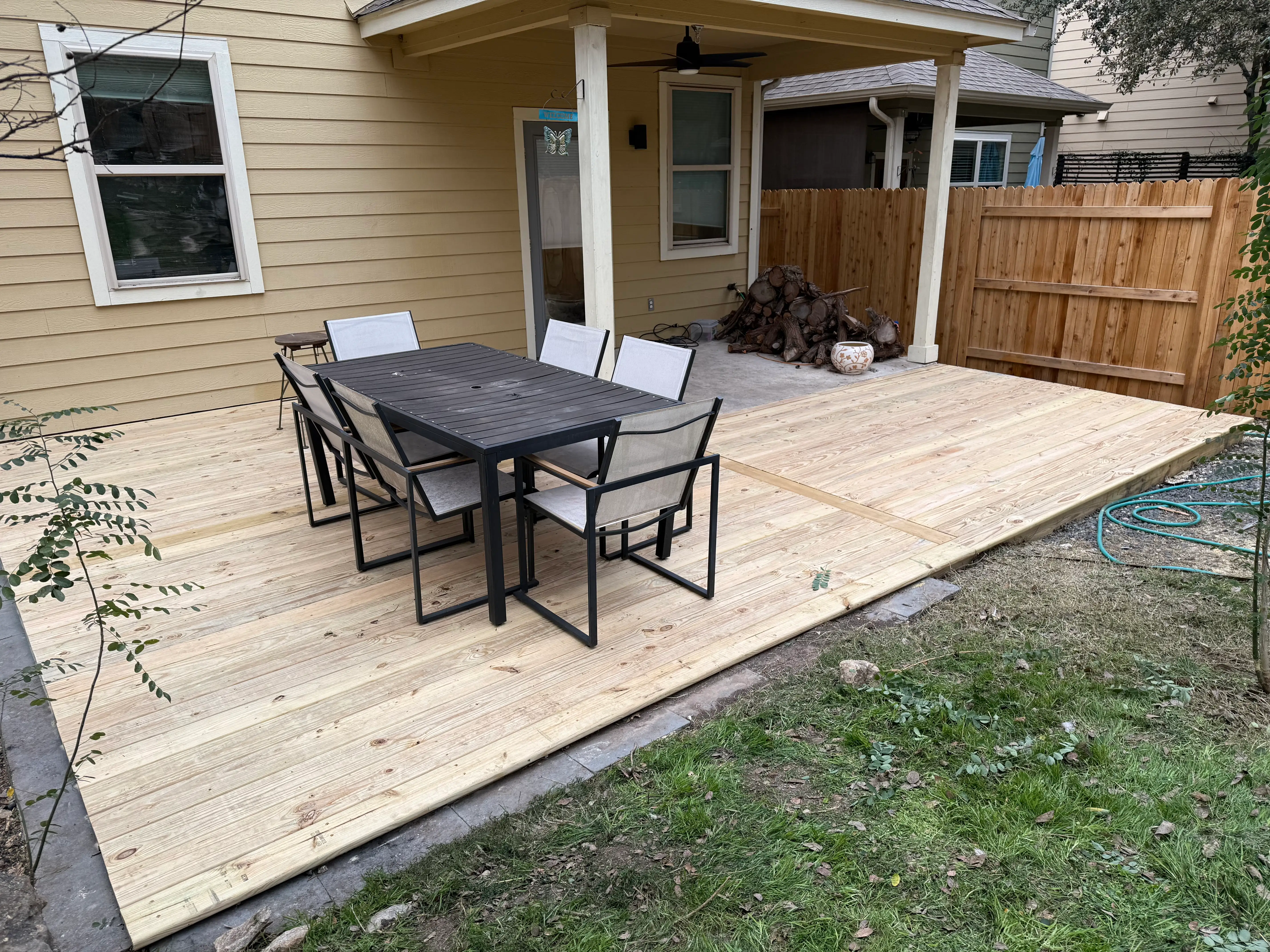 Ground-level treated pine deck off the back of a home with an outdoor dining set