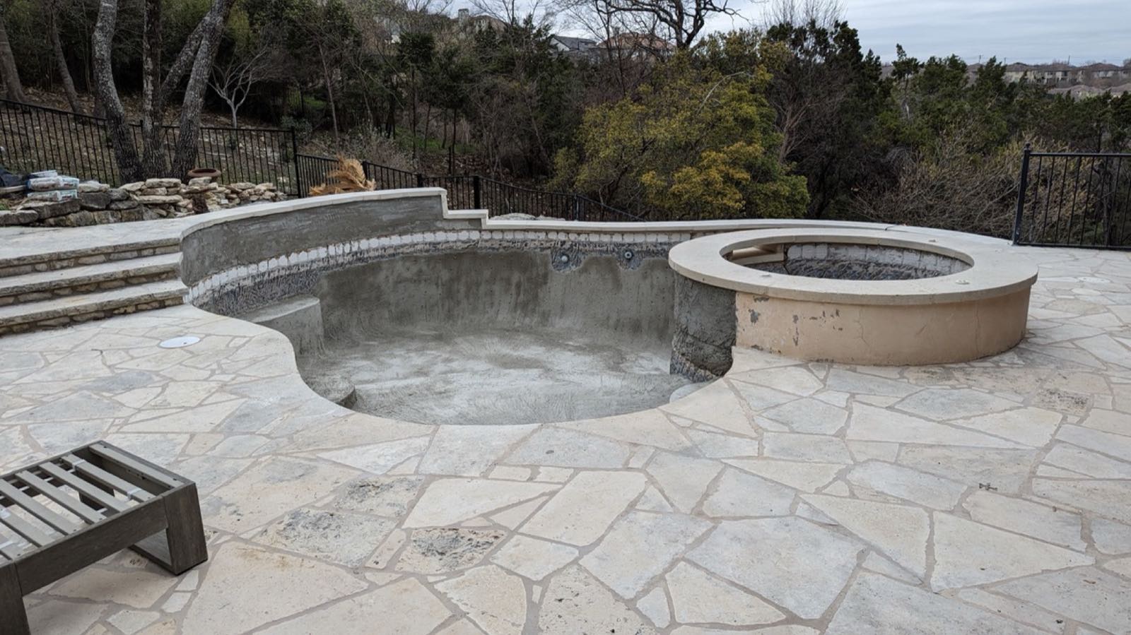 Before: the pool deck in irregular flagstone, with the old mixed-material steps climbing away at the left
