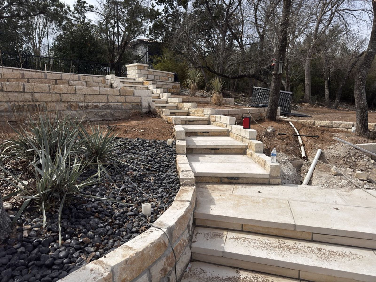 Large limestone slab treads under construction, climbing from the pool terrace to the upper patio