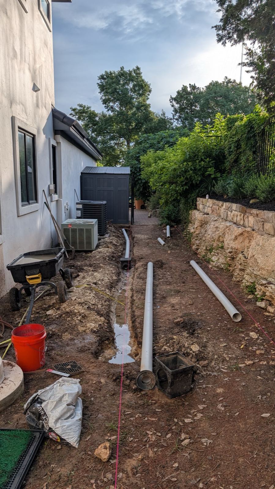 Four-inch PVC and catch basins going in along the side yard, tied to the downspouts